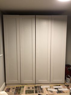 a room with white cupboards and papers on the floor