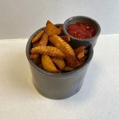 a cup filled with french fries and ketchup sitting on top of a table