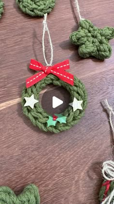 crocheted christmas wreath ornaments hanging on a wooden table with red and green ribbons