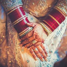 the bride's hands are adorned with red and gold bracelets