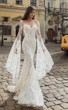 a woman in a white dress standing on a cobblestone street