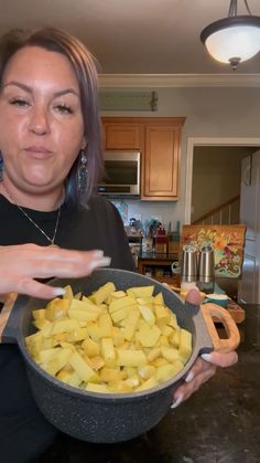 a woman holding a bowl full of cut up potatoes