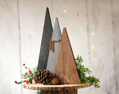 three wooden christmas trees on top of a tree stump with pine cones and evergreens