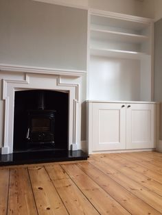 an empty room with a fireplace and white cabinets