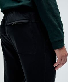 a man wearing black pants and a green shirt is holding his hand in his pocket