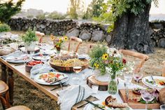 an outdoor table set with plates and glasses