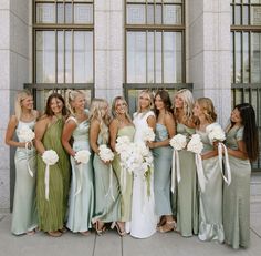 a group of women standing next to each other in front of a building with windows