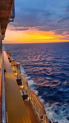 the deck of a cruise ship as the sun sets over the ocean and lights shine brightly