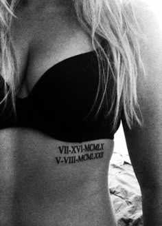 black and white photograph of a woman's stomach with roman numeral tattoo