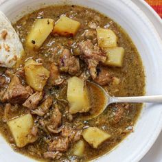 a white bowl filled with stew and some tortilla bread on top of it