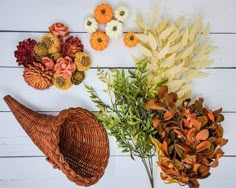 three different types of fake flowers on a white wooden background with pumpkins and gourds