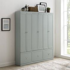 a blue armoire in a white room with pictures on the wall and framed photos above it