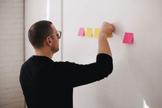 a man writing on a wall with sticky notes