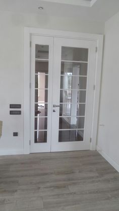 an empty room with two glass doors and wood flooring on either side of the door