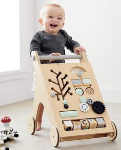 a baby sitting in a wooden walker with lots of magnets on it's side