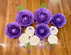 purple and white paper flowers sitting on top of a wooden floor