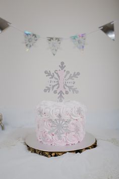 a frosted cake sitting on top of a wooden table next to bunting flags