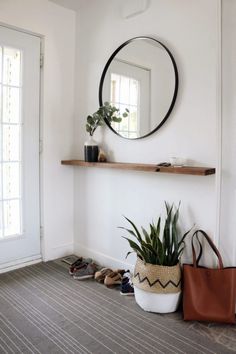 a room with a mirror, potted plant and shoes on the floor