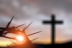 the sun is setting behind a crucifix with a cross in the background