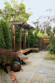 a wooden bench sitting on top of a stone walkway next to a lush green forest