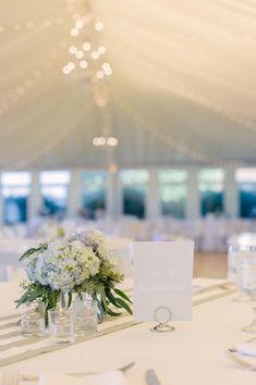 the table is set with white flowers and silverware