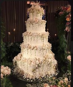 a large white wedding cake sitting on top of a table next to flowers and greenery