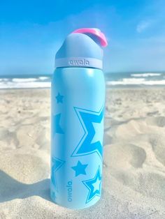 a blue water bottle sitting on top of a sandy beach