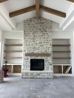 an empty living room with a fireplace and shelves