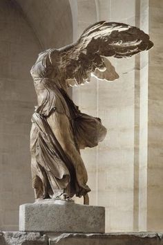 an angel statue with its wings spread out in front of a wall and columns on either side