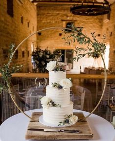 a wedding cake with white flowers and greenery is on a table in an old building