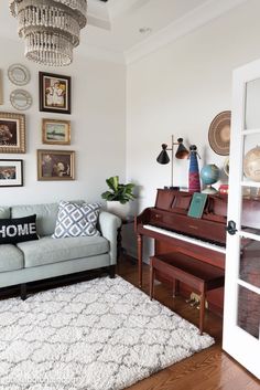 a living room with a couch, piano and many pictures on the wall above it