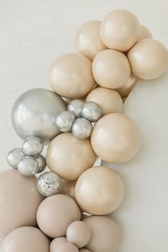 an arrangement of white and beige balloons on a wall