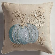 a decorative pillow with blue pumpkins embroidered on the front and sides, sitting on a white surface