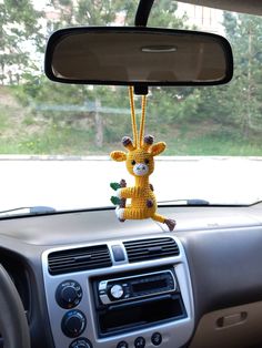 a stuffed giraffe hanging from the dashboard of a car