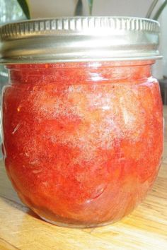 a jar filled with red liquid sitting on top of a wooden table