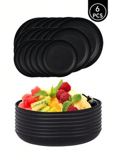 six black plastic plates in a bowl with raspberries, pineapples and kiwi