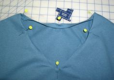 there is a blue shirt with buttons on the front and back of it, next to a cutting board