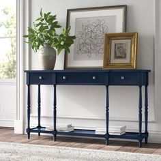 a blue console table with two drawers and a potted plant next to it on top