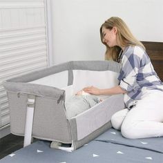 a woman sitting on top of a bed next to a baby crib