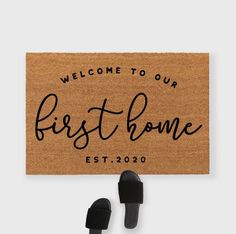 a welcome mat with black slippers hanging from it and the words, welcome to our first home