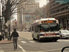 a man walking across the street in front of a bus on a busy city street