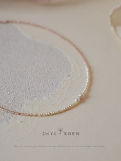 a close up of a necklace with pearls on it's end and the word jasmo written in japanese