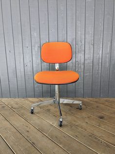 an orange office chair sitting on top of a wooden floor