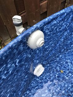 an above ground swimming pool with blue water and white faucets in the middle