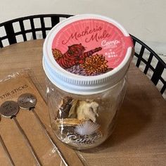 a jar filled with lots of stuff sitting on top of a table next to a pair of scissors