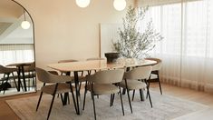 a dining room table with six chairs and a large mirror in the corner next to it