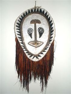 a mask hanging on the wall with fringes around it's face and eyes