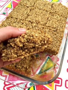 a person holding up a piece of granola in their left hand, with the rest of the bar partially eaten