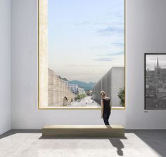 a woman standing in front of a window looking at buildings