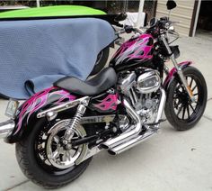 a pink and black motorcycle parked next to a blue blanket on the back of it